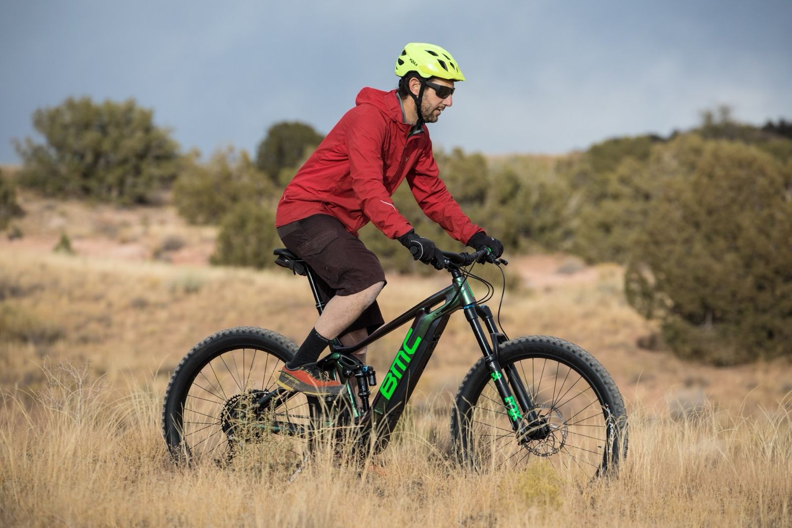 A woman in a helmet riding an electric mountain bike with canyon cliffs behind